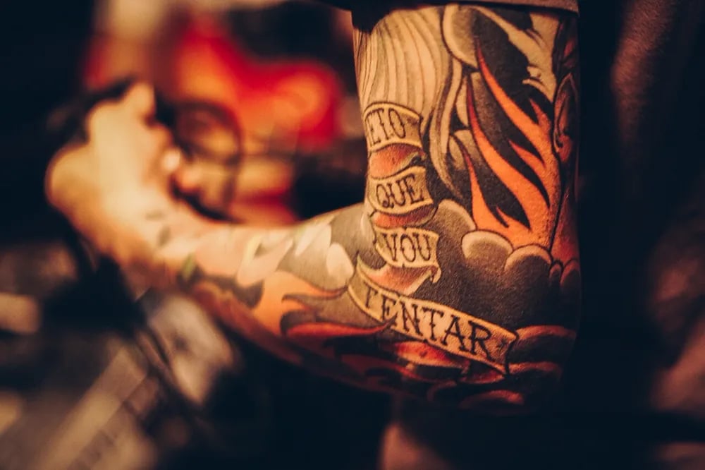 Forearm sleeve with flames, clouds and script lettering in warm light